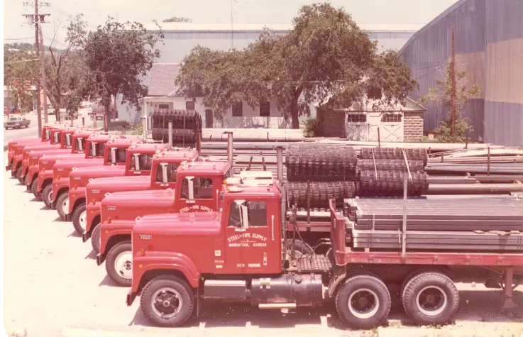 Historic 1975 photo of the Steel and Pipe Supply red truck fleet loaded with pipe