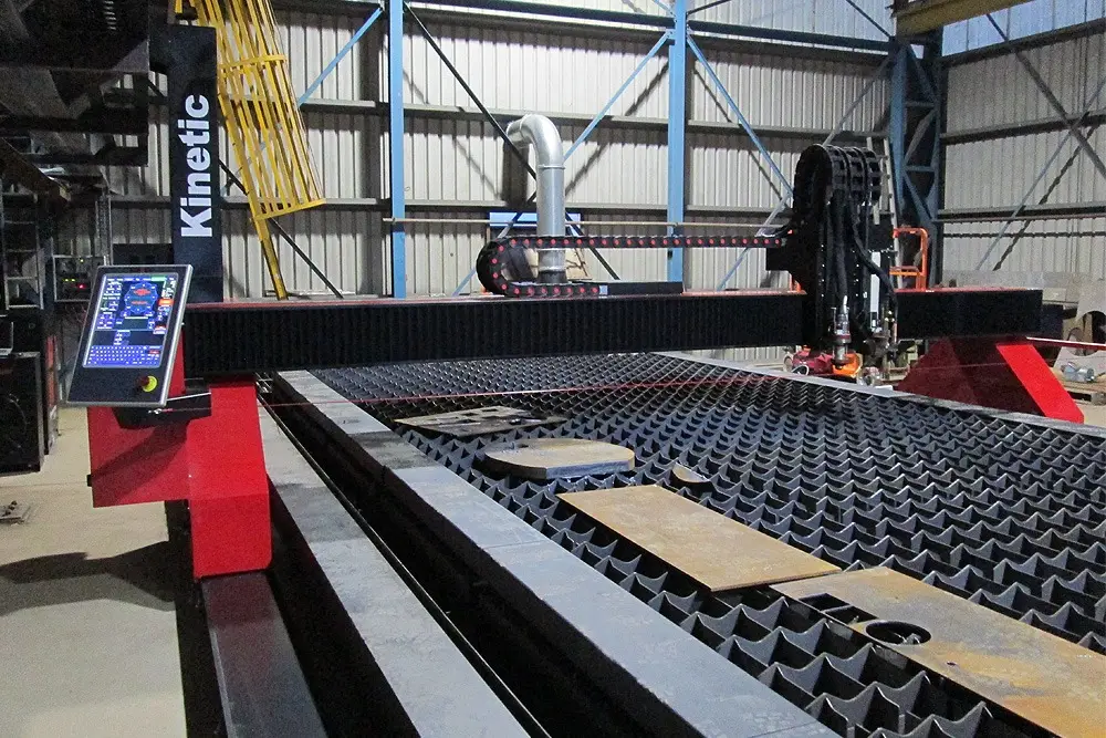 Kinetic K2500 plasma cutting table with cut steel plate on the bed