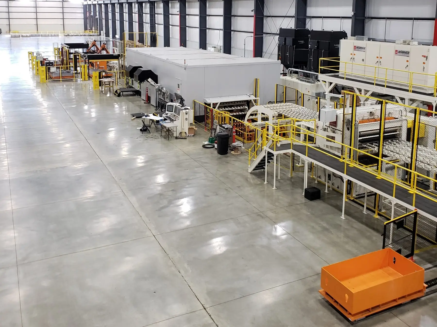 Coil-fed laser blanking line running down a long, bright processing bay