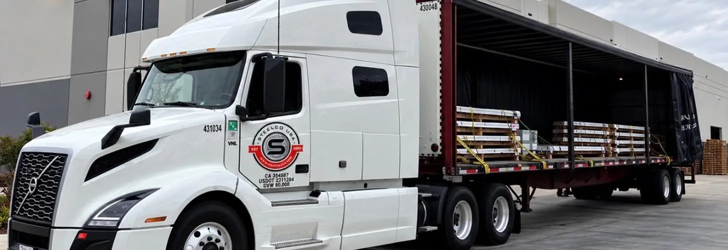 SteelCo USA tractor with an open curtain-side trailer loaded with steel at the dock