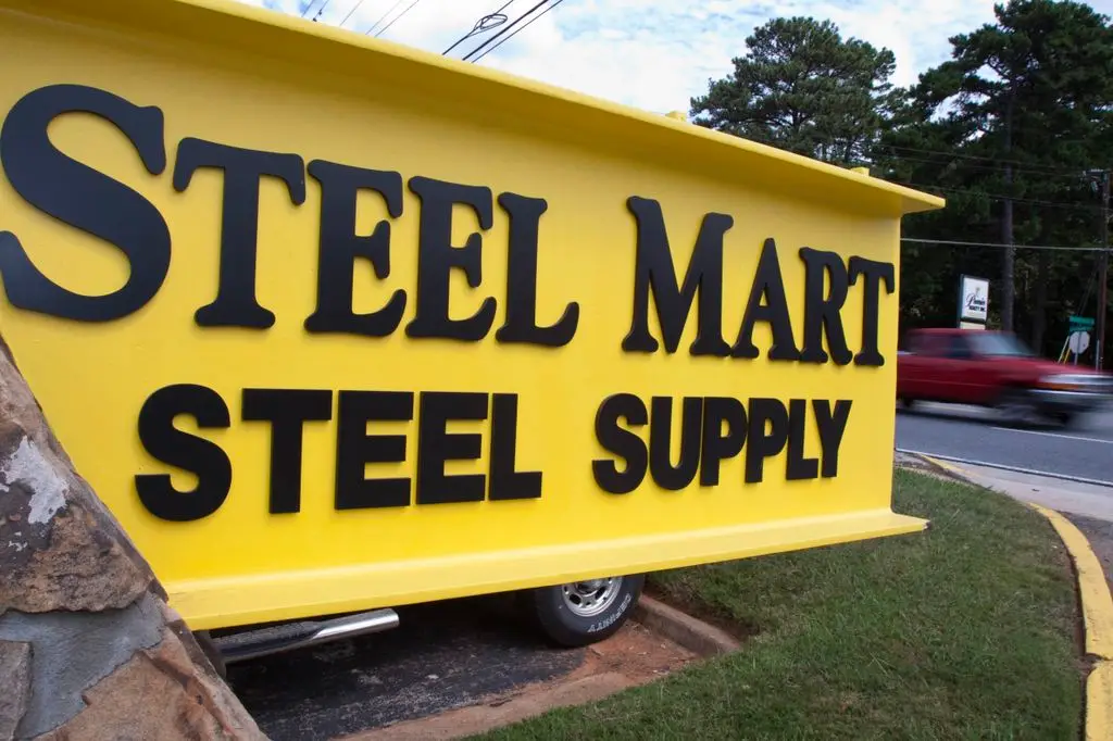 Yellow I-beam sign reading SteelMart Steel Supply at the company's entrance