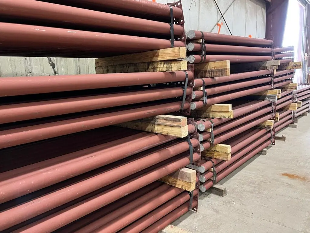 Racks of steel pipe stacked on wooden dunnage in a Sugar Steel warehouse