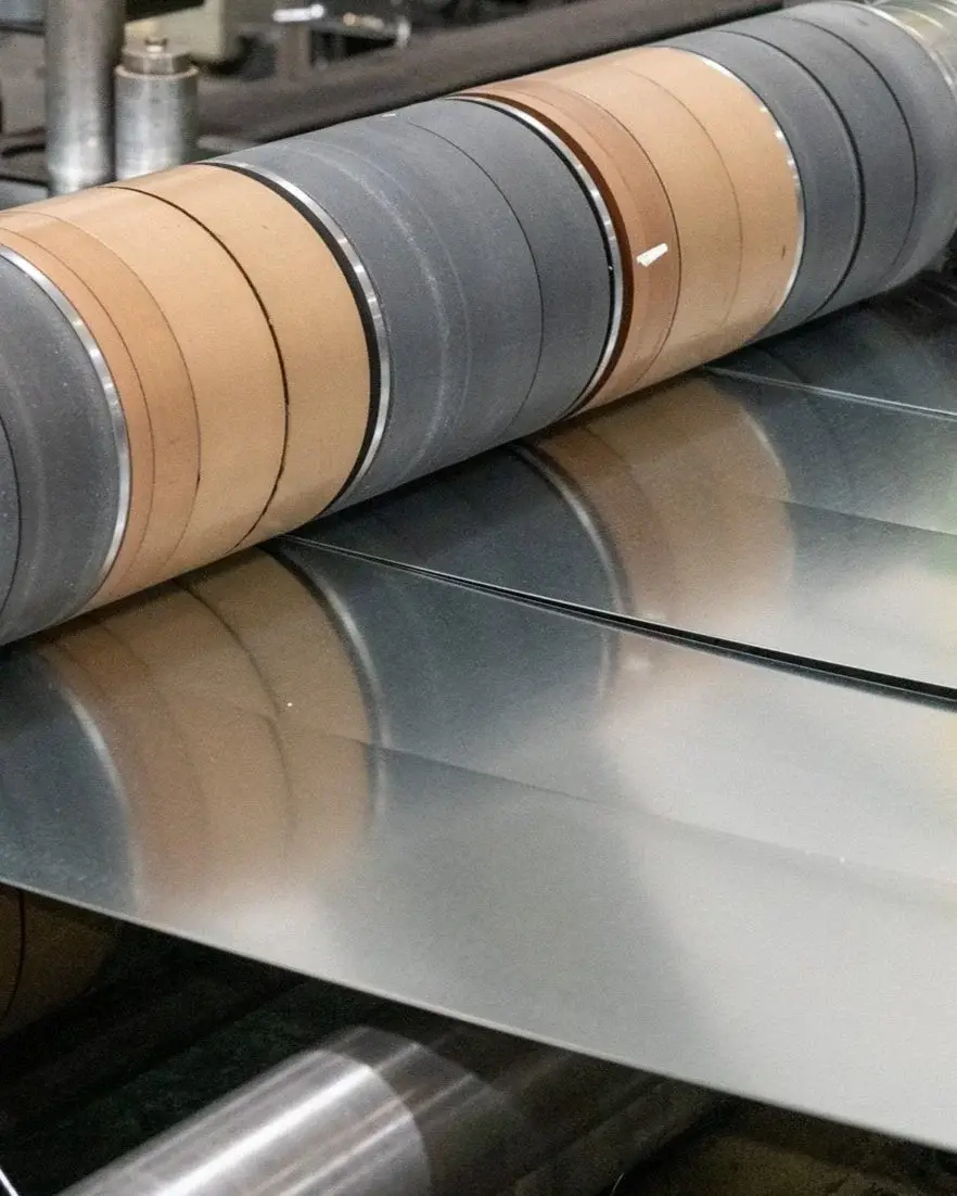 Close-up of slit steel strands passing over the rolls of a Universal Metals slitting line