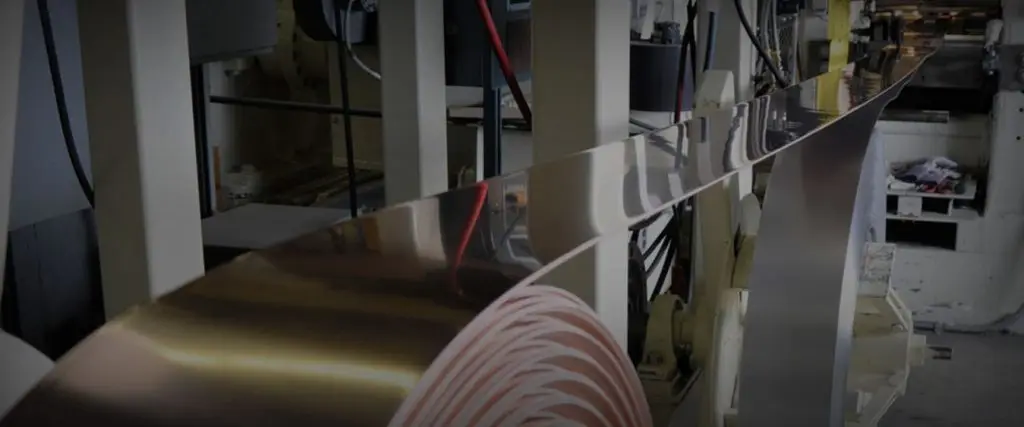 Copper strip coil running through a rolling and recoiling line at Vincent Clad Metals