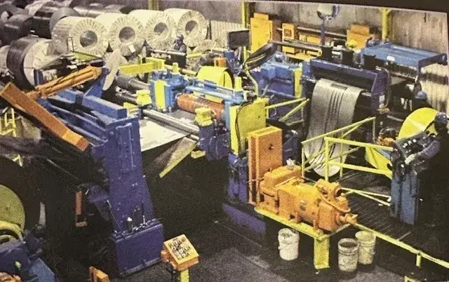 Slitting line with uncoiler, slitter head and recoiler, with steel coils staged behind
