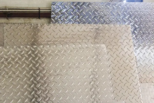 Plate shear with cut steel plates stacked beside it at Woodward Steel
