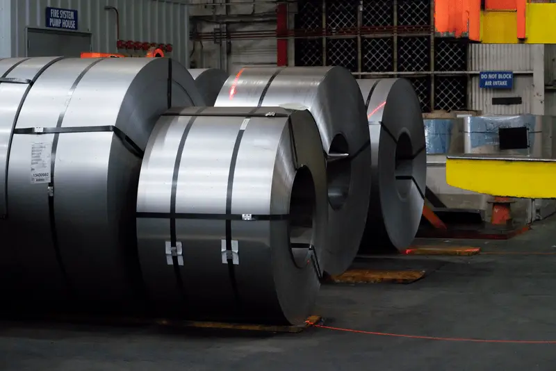 Banded flat-rolled steel coils staged on the floor of a Worthington Steel processing plant